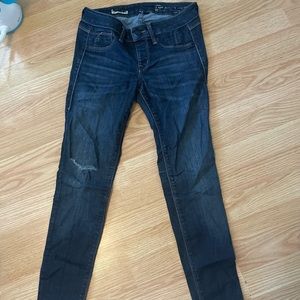 Dark wash, slightly distressed skinny jeans, worn moderately